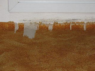 Rozpárané okraje koberce před balkónovým prahem